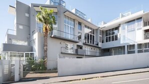 Een modern meerlaags gebouw met balkons, grote ramen en een hekwerk.