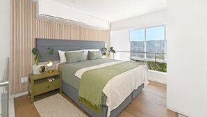 Een moderne slaapkamer met een groot bed, nachtkastjes, stadszicht en een balkon.