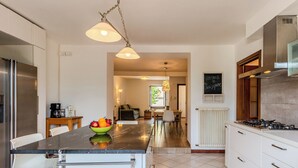 A modern kitchen with a central island, stainless steel appliances, and a dining area with a view. - Legnone by Interhome (Sorico Albonico)