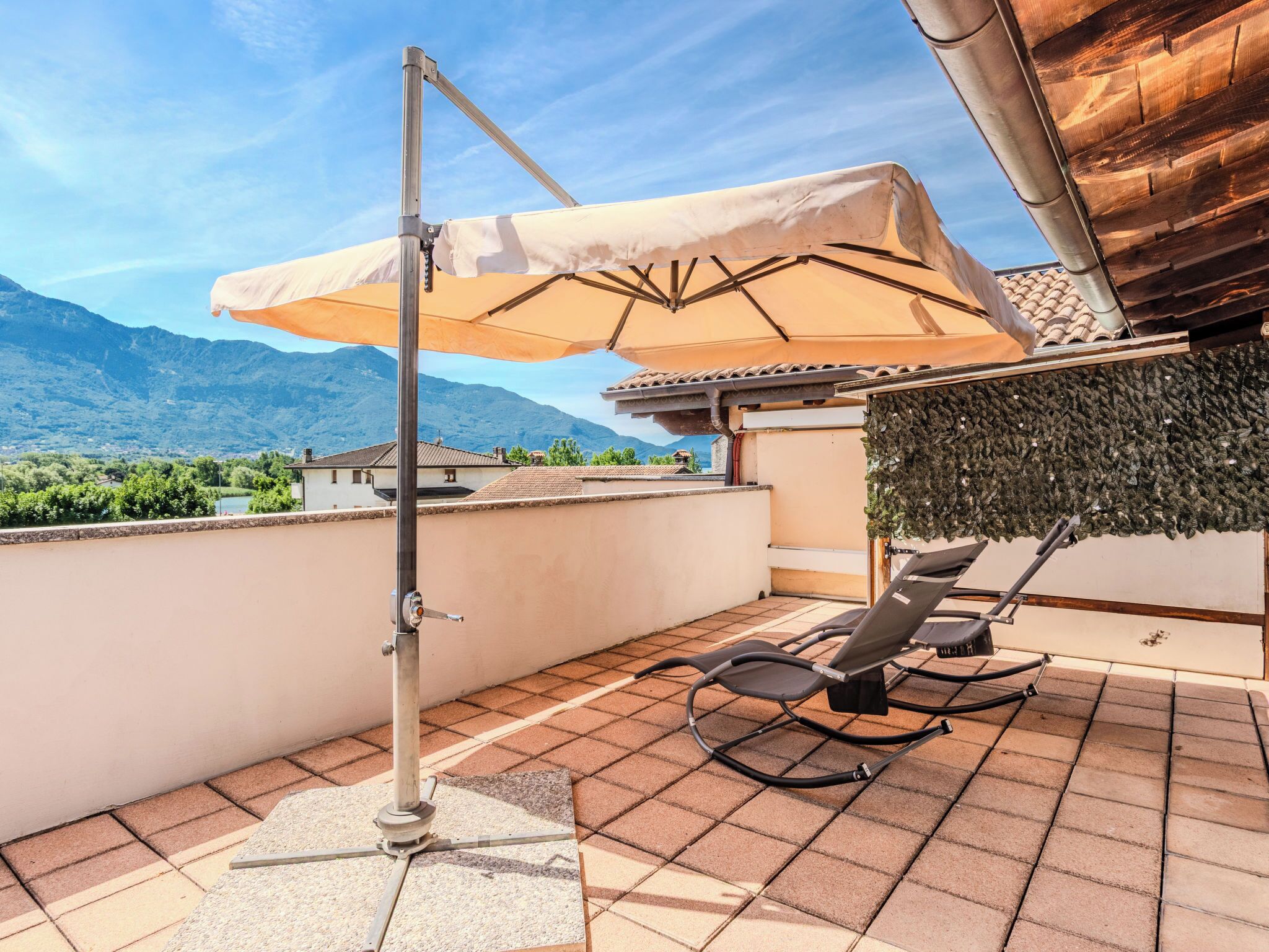 Terraza en la azotea con toldo retráctil, una silla de descanso y vistas a las montañas.