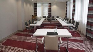 Una sala conferenze con un lungo tavolo, sedie, un proiettore e un pavimento rivestito di moquette.