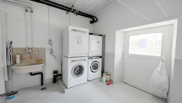 A laundry room with two washing machines, a sink, and a window.