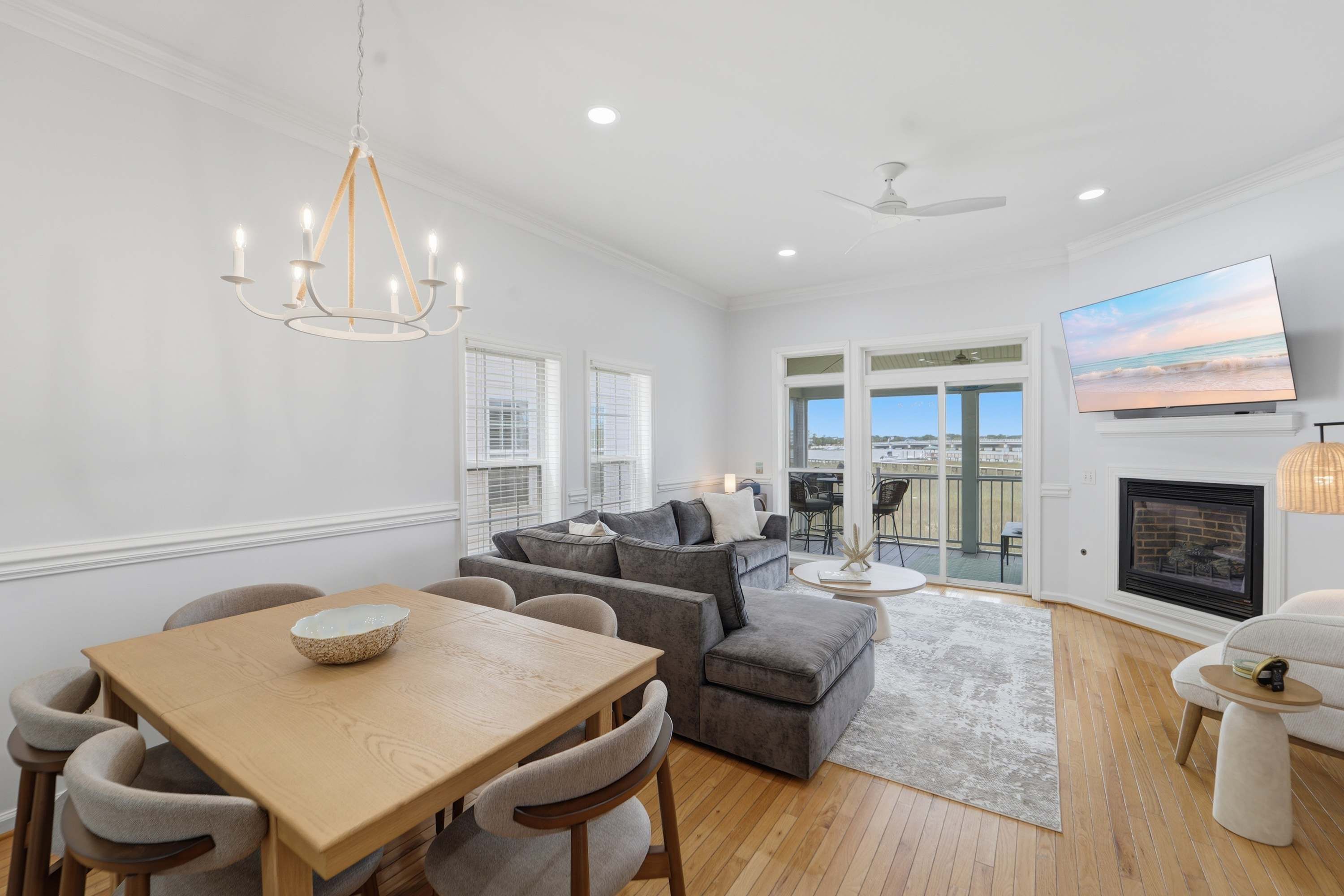 A modern living room with a dining area, a fireplace, and a large TV on the wall.