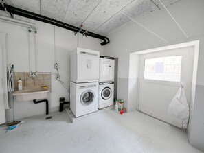 Ein Waschraum mit zwei Waschmaschinen, einem Waschbecken und einem Fenster.