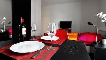Un coin repas avec une table mise pour deux, une bouteille de vin et un verre.