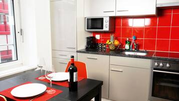 Une cuisine compacte équipée d’un four à micro-ondes, d’une cuisinière et d’un coin repas avec une table dressée pour deux personnes.