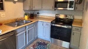 A kitchen with a stainless steel stove, microwave, double sink, and light-colored cabinets.