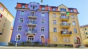 Um edifício com várias andares, varandas e uma porta vermelha.