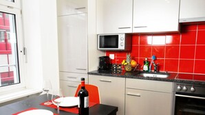 Uma cozinha compacta com micro-ondas, fogão e área de refeições com mesa posta para dois.