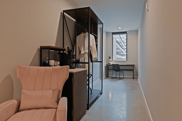 A modern room with a large window, a desk, a chair, and a wardrobe.