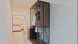 Una habitación de hotel moderna con vestidor, cama, escritorio y silla.
