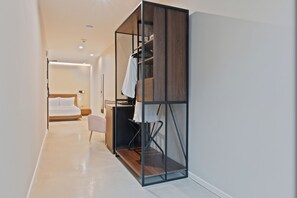 Quarto de hotel moderno com closet espaçoso, uma cama, escrivaninha e cadeira.