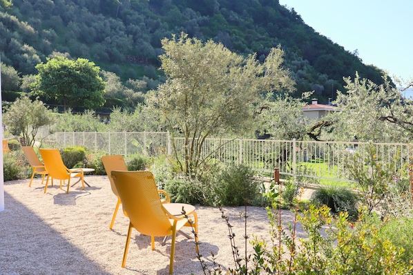 A patio with yellow chairs, a gravel ground, and a white fence. - In a Residence, Air-conditioned, Large Outdoor Space (Marone)