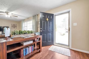 A room with a wooden desk, bookshelves, a black door, and a window with curtains. - Peachtree City Home Near Lake with Yard & Firepit (Peachtree City)