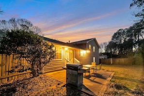 A two-story house with a covered patio, a barbecue grill, and a wooden fence. - Peachtree City Home Near Lake with Yard & Firepit (Peachtree City)
