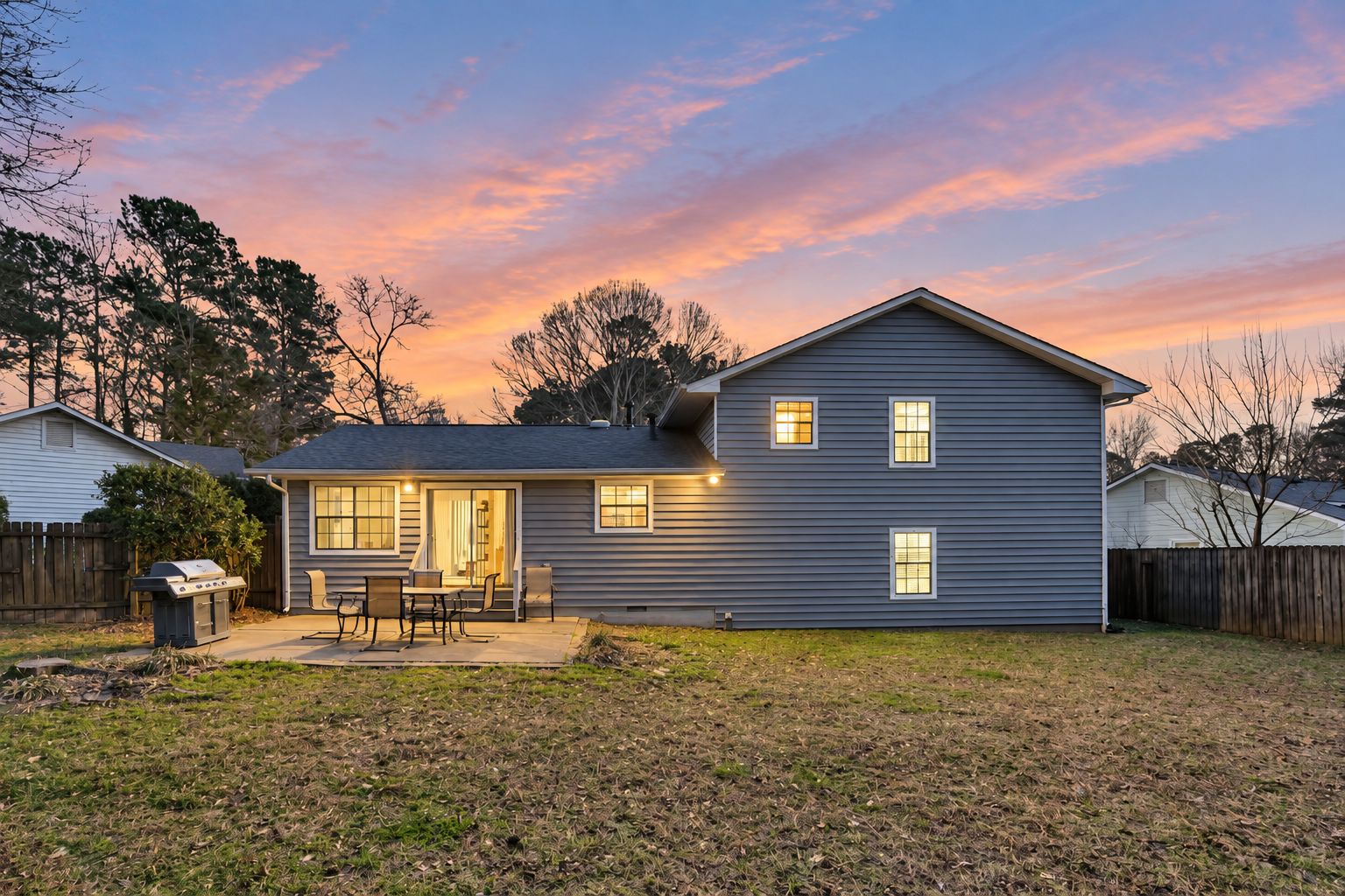 A two-story house with a patio and a barbecue grill.