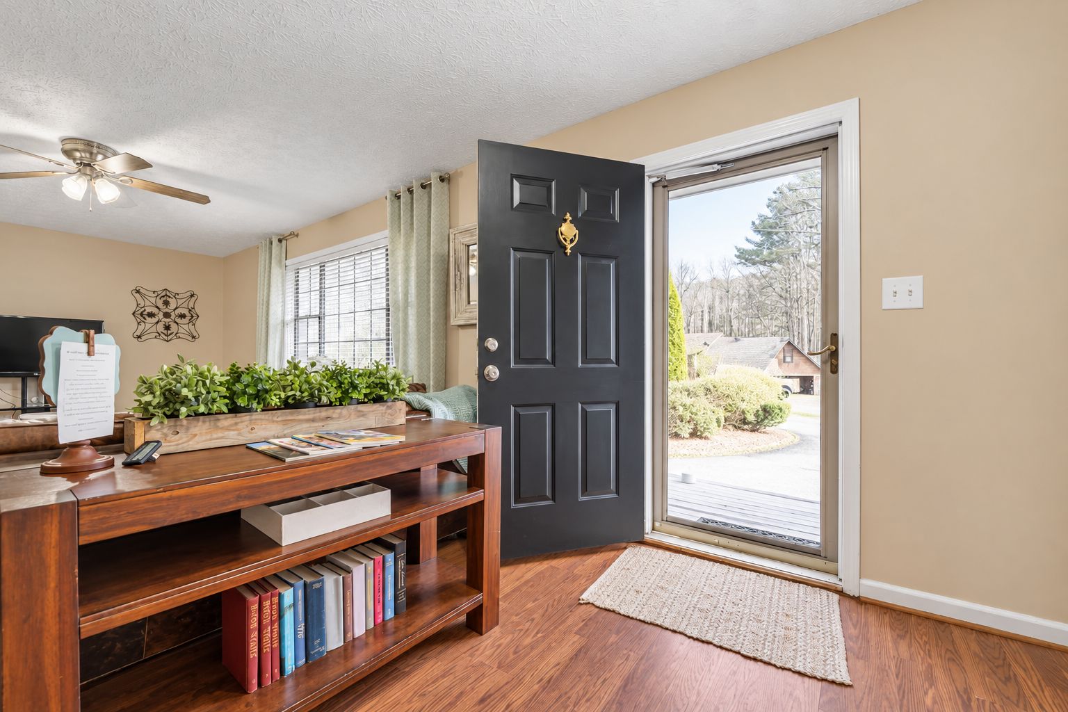 A room with a wooden desk, a bookshelf, a black door, and a view through the door.