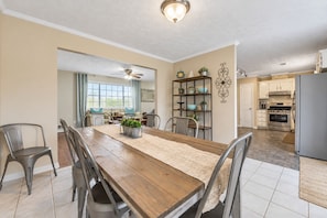 A spacious kitchen with a dining area, featuring a wooden table, chairs, and a built-in bookshelf. - Peachtree City Home Near Lake with Yard & Firepit (Peachtree City)