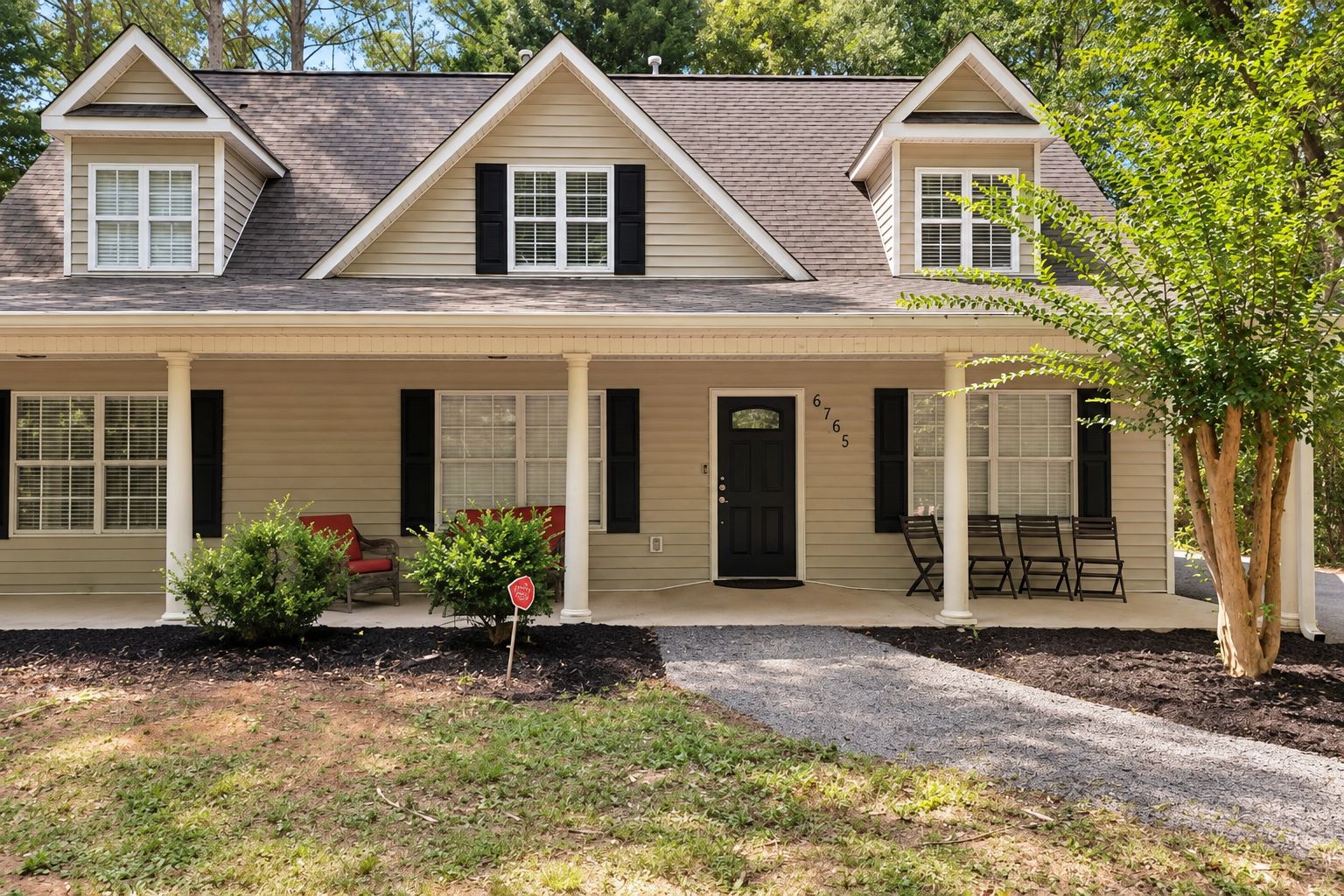 A two-story house with a porch, a front door, and a mailbox.