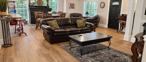 A spacious living room with a leather sofa, a coffee table, and a patterned rug.