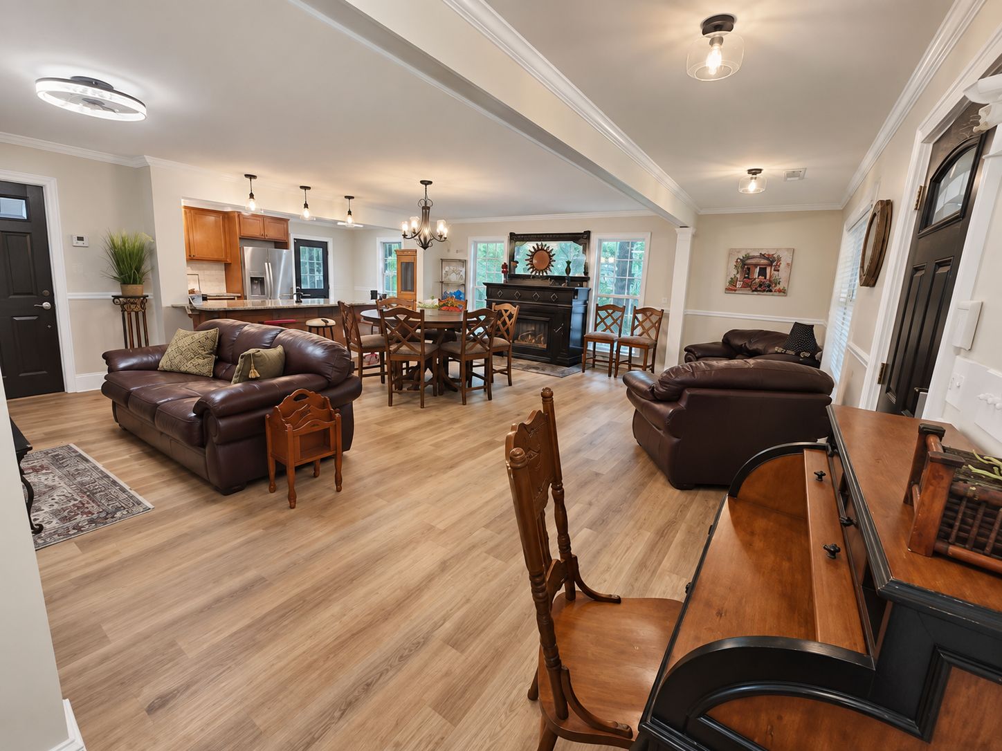A spacious living area with a fireplace, leather sofas, wooden dining table, and a kitchen in the background.