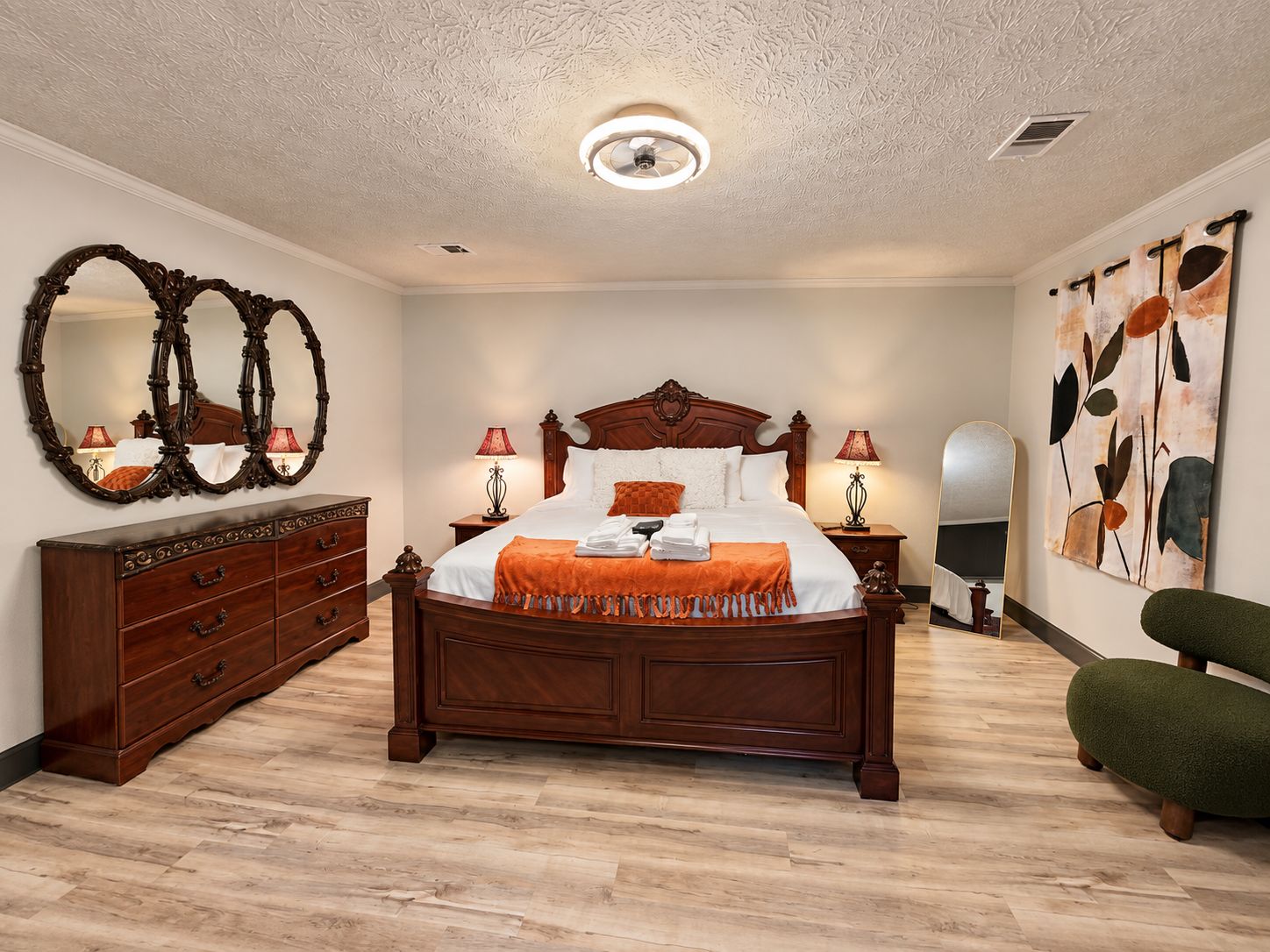 Een slaapkamer met een groot bed, een dressoir, een spiegel en een decoratie aan de muur.