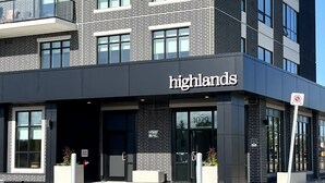 Ein modernes Gebäude mit einem 'Highlands'-Schild, großen Fenstern und einem Parkplatz.
