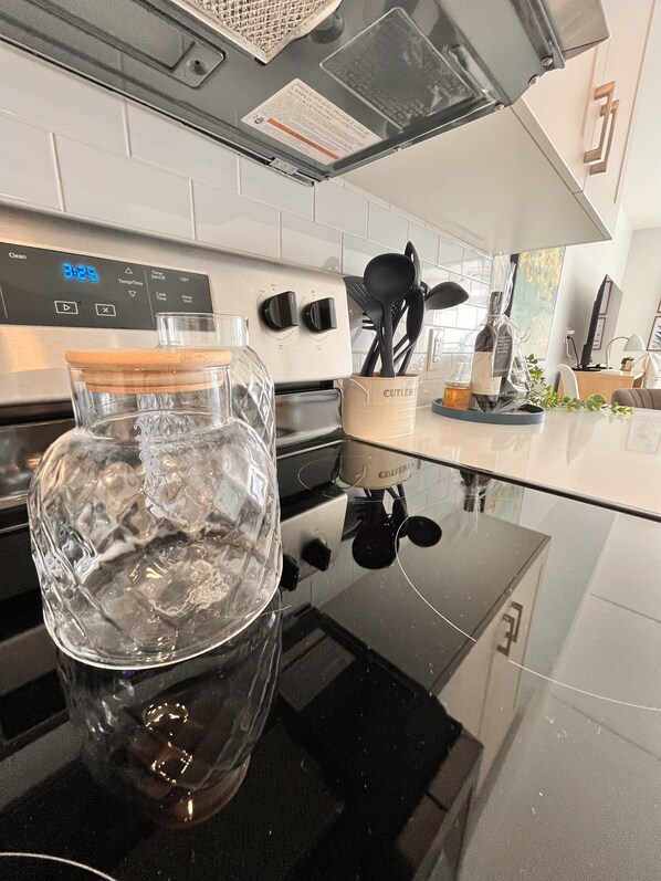 A kitchen with a glass container on the counter, a digital clock, and a coffee maker.