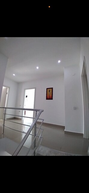 A spacious room with a high ceiling, a metal staircase, and a framed picture on the wall.