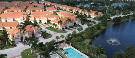 Zona residencial com piscina, cercada por casas com telhados vermelhos e palmeiras.
