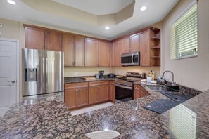 A kitchen with granite countertops, stainless steel appliances, wooden cabinets, and a window with blinds. - Relaxed Florida Living | Gated Community with Heated Pool | Near Beaches, Shopping & Dining (Fort Myers)