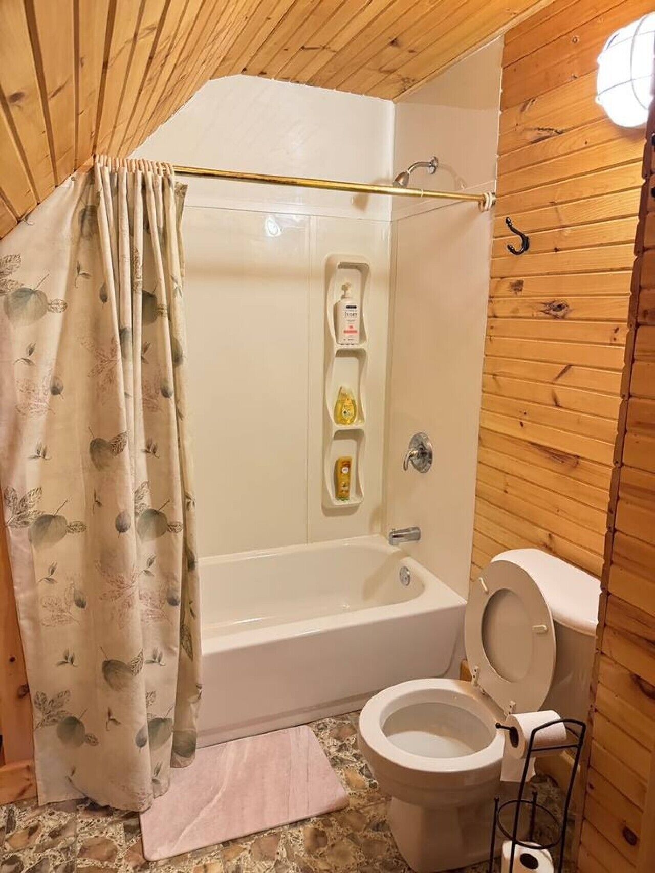 Et badeværelse med badekar, toilet og bruseforhæng.