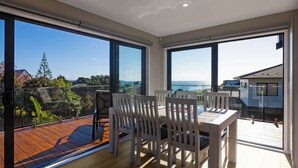 Un intérieur moderne avec de grandes fenêtres, une terrasse en bois et un coin repas.