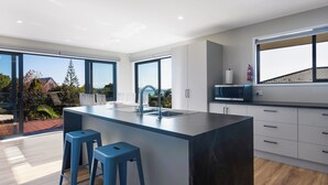Une cuisine moderne dotée d’un grand îlot central, de tabourets de bar, d’un four à micro-ondes et offrant une vue sur l’extérieur.