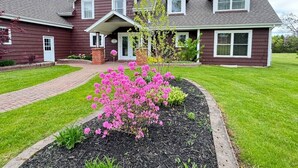 A two-story house with a front porch, a driveway, and a well-maintained lawn. - Cedayway Riverview Estate-by Brudenell River overseeing golf course (Montague)