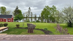 A red barn, a wooden deck, a well-maintained lawn, and a variety of trees. - Cedayway Riverview Estate-by Brudenell River overseeing golf course (Montague)