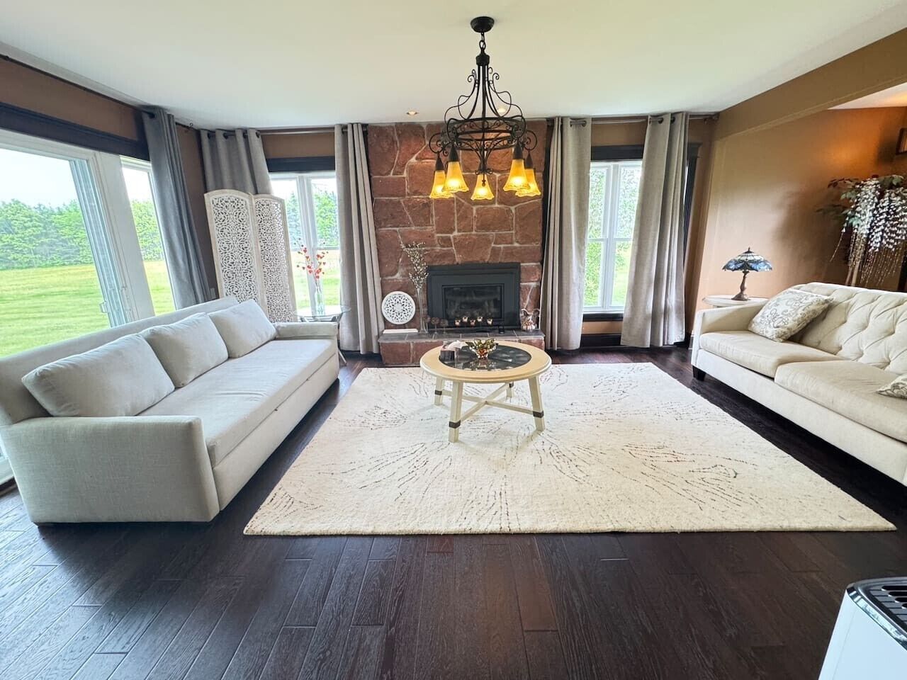 A living room with a fireplace, two sofas, a coffee table, and a chandelier.