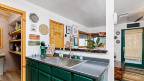 A kitchen with green cabinets, a sink, and various kitchen items. - River Falls - Hot Tub and Mountain Views sleeps 4 (Oakhurst)
