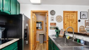 A kitchen with green cabinets, a stainless steel sink, and a refrigerator. - River Falls - Hot Tub and Mountain Views sleeps 4 (Oakhurst)