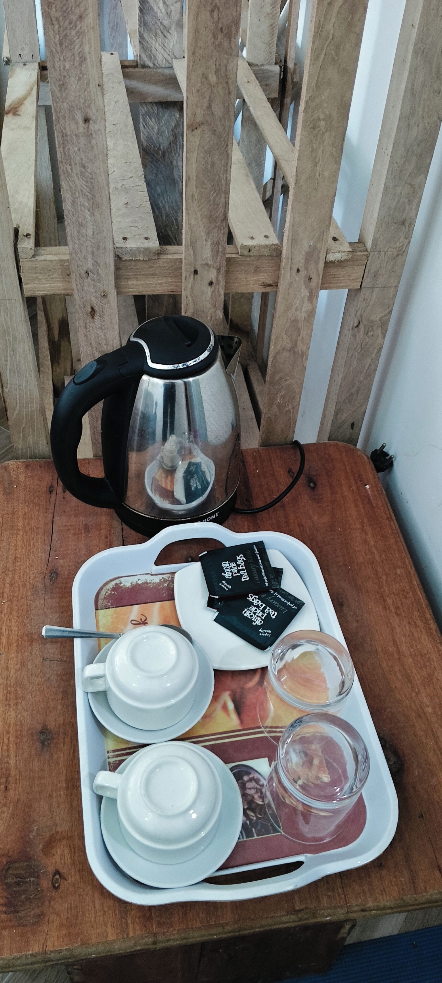 A tray with tea sets and a kettle on a wooden table.