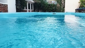 A clear blue pool with a stone wall and greenery in the background. - Primavera Jambiani (Jambiani)