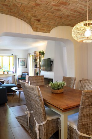 A dining area with wicker chairs, a wooden table, and a woven light fixture. - Algarve escape in the heart of the prestigious Golden Triangle (Quarteira)