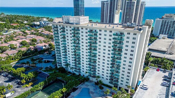 Un hôtel de grande hauteur doté d’une piscine, de courts de tennis et offrant une vue sur l’océan.