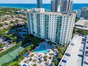 Un hôtel de grande hauteur doté d’une piscine, de courts de tennis et offrant une vue sur l’océan.