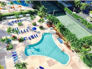 A swimming pool with lounge chairs and palm trees. - Bright 1 Bedroom Near Beach & Shops (Sunny Isles Beach)