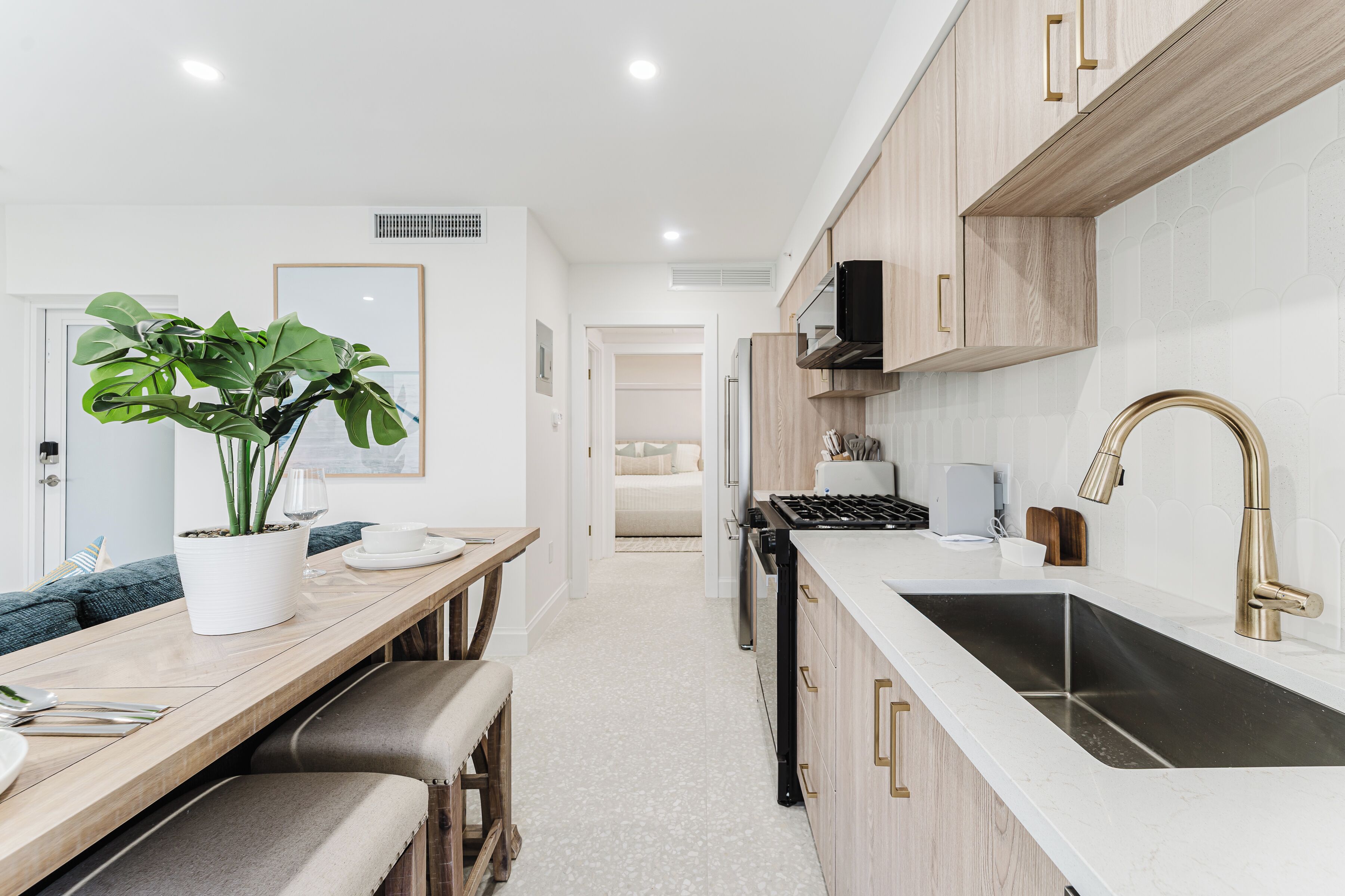 A modern kitchen with a wooden countertop, a sink with a gold faucet, and a potted plant.