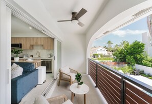 Ein Balkon mit Deckenventilator, einer Couch, einem kleinen Tisch und einem Blumentopf.