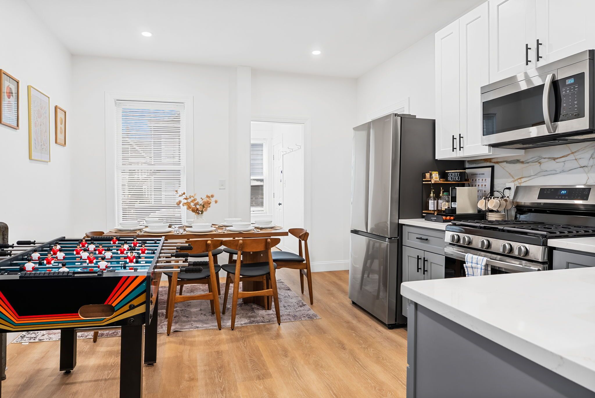 A modern kitchen with a foosball table, stainless steel appliances, and a dining area with a table and chairs.