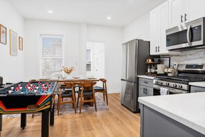 Eine moderne Küche mit einer Tischfußballmaschine, Edelstahlgeräten und einem Essbereich mit Tisch und Stühlen.