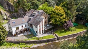 Una casa de dos pisos con un balcón, una escalera y un pequeño jardín.